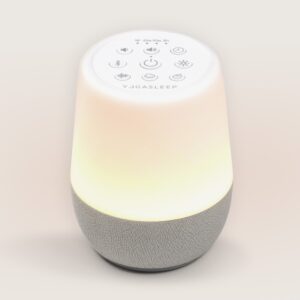 Front view of Duet bedside sound machine showing lit night light, top controls, and gray fabric speaker base on beige