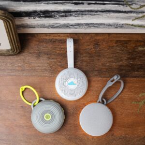 Top view of three Hushh portable white noise machines with clips and circular speaker grilles on a wooden surface