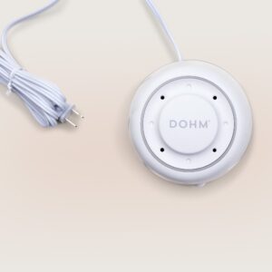 Top view of Dohm white noise machine showcasing circular vented housing, DOHM logo, and coiled power cord on a beige background
