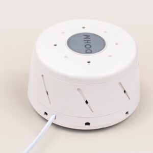 Angled top-front of Dohm Classic showing circular top badge, side vents, and power cord on beige background