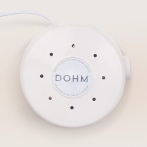 Top-down view of Dohm Classic showing round white housing, DOHM logo, and vent holes on beige background