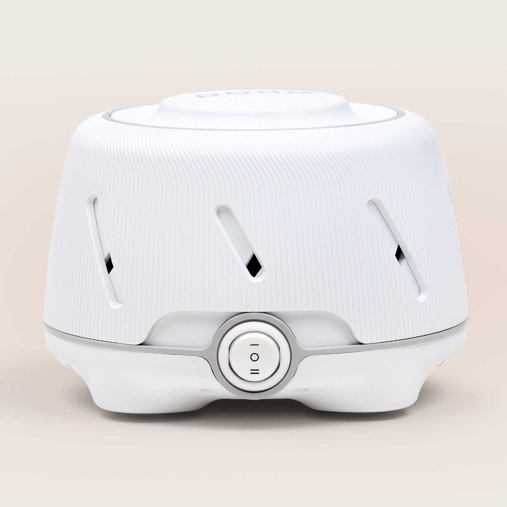 Front view of Dohm white noise machine showcasing ribbed white housing and center two-speed power switch on a soft beige background