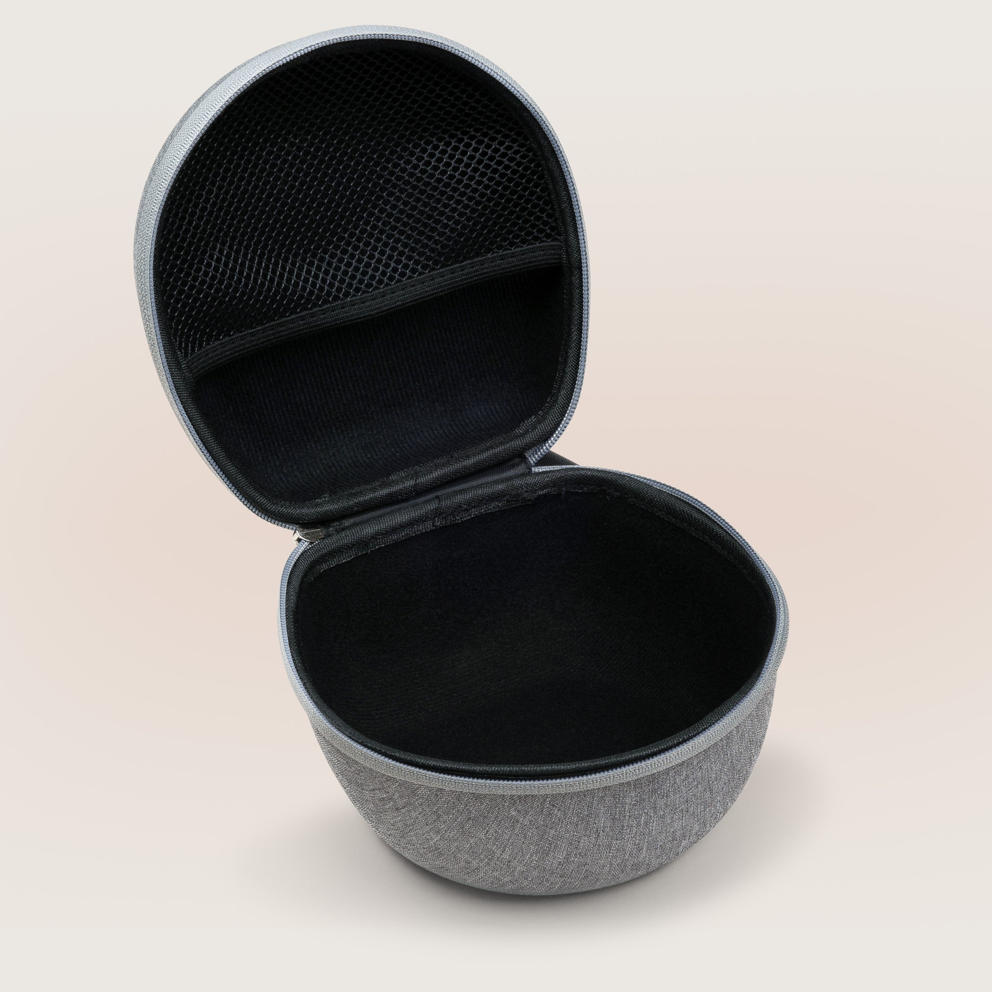 Angled top view of Dohm travel case showing open interior with zippered mesh pocket and padded black lining on pale beige background
