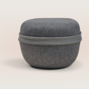 Three-quarter view of Dohm Travel Case showing gray linen exterior, zip closure, and rounded compact shape on a neutral background