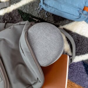 Gray Dohm travel case inside an open backpack on a patterned rug