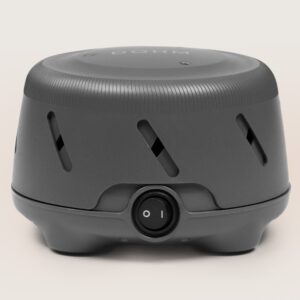 Front view of Dohm Uno charcoal white noise machine showing front rocker switch and diagonal vents on a light linen background