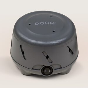 Front view of charcoal Dohm Uno white noise machine showing power switch and angled ventilation slots on a beige background