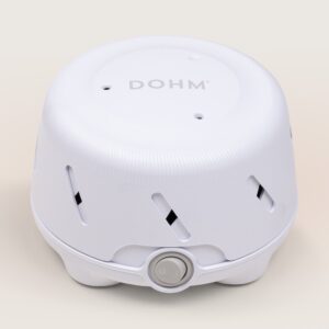 Angled top view of Dohm Uno sound machine with white housing, DOHM logo, vent slots, and front power dial on beige background
