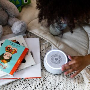 Child reaching for white Dreamcenter sound machine with lit color night light inside a play tent