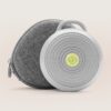 Front view of Hushh sound machine with carry loop and gray fabric travel case showing perforated grille on a light beige background