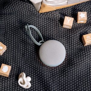 Top view of Hushh 2 sound machine showing fabric speaker grille and silicone loop on dark knit blanket