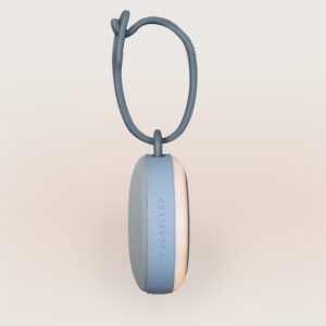 Side view of Hushh 2 sound machine showcasing silicone hanging loop and fabric speaker grille on a pale background