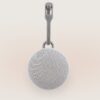 Front view of Hushh 2 portable sound machine with round speaker grille and Yogasleep hanging strap on a soft beige background