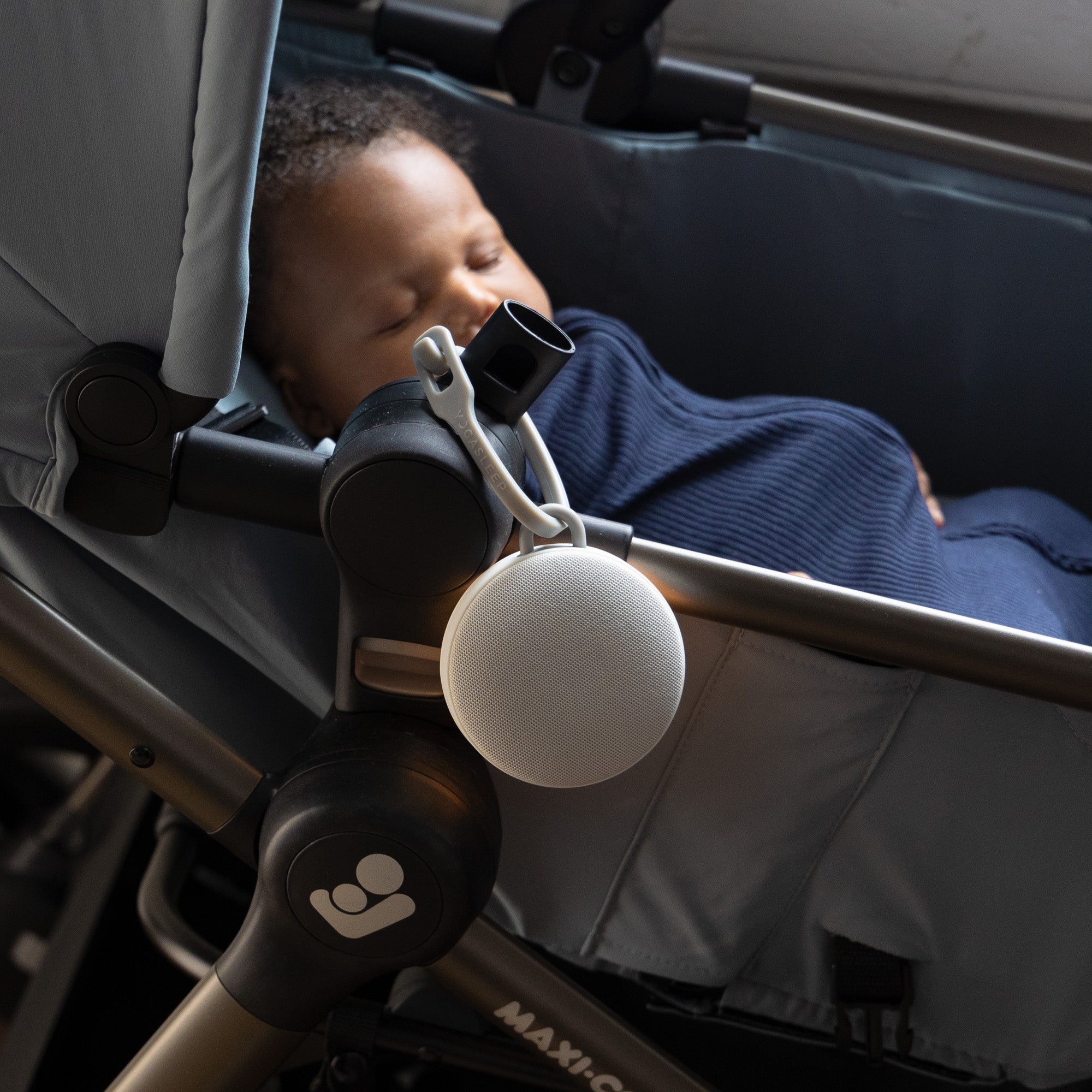 Baby in stroller listening to Hushh 2 portable sound machine attached by silicone strap