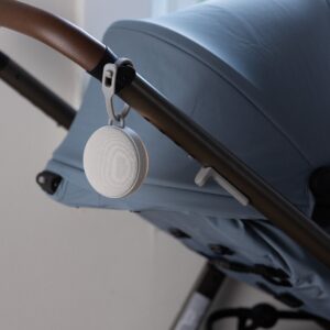 Hushh 2 sound machine clipped to stroller by silicone strap, caregiver holding baby in background