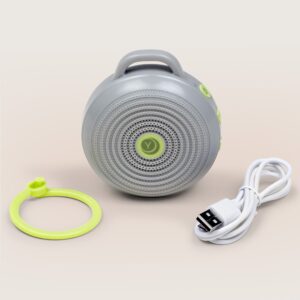 Front view of Hushh portable sound machine showing circular speaker grille, top handle, lime green clip and USB charging cable on pale background