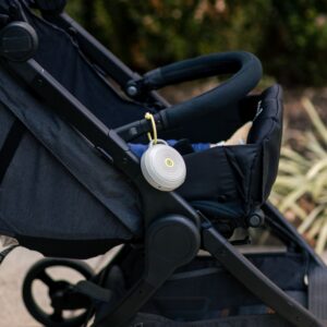 Hushh portable white sound machine clipped to a stroller handle outdoors