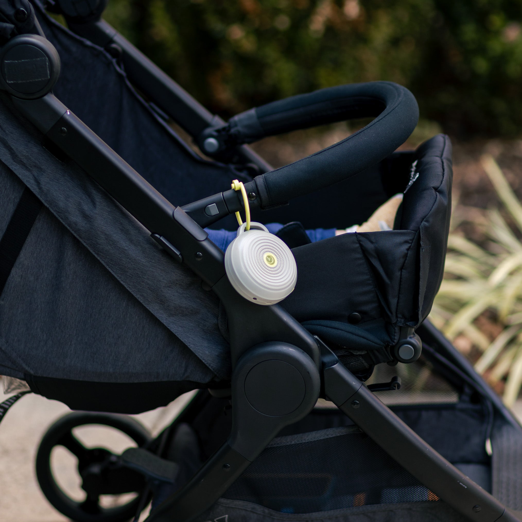 Hushh portable white sound machine clipped to a stroller handle outdoors